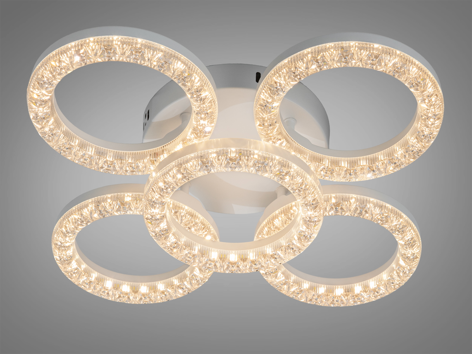 Стельовий світильник з теплим світлом, виконаний у формі чотирьох кілець з кришталевими елементами.
