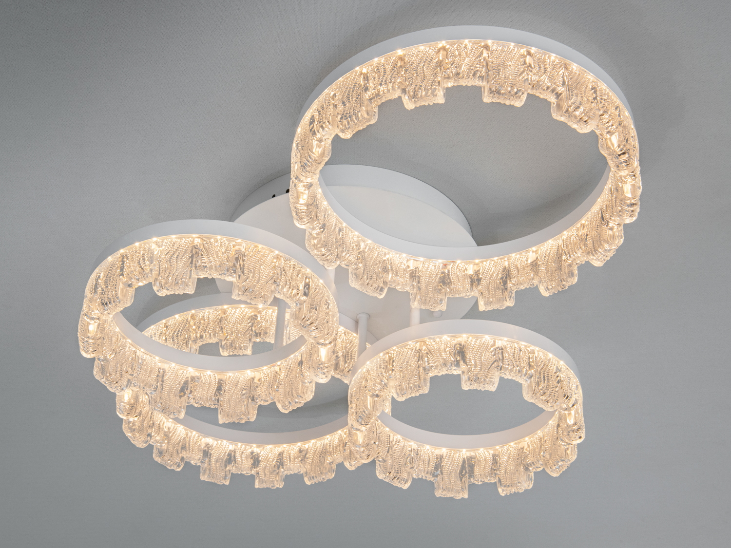 Світильник з чотирма кільцями, виконаними з прозорого матеріалу, що імітує крижані візерунки. Підходить для сучасного інтер’єру.