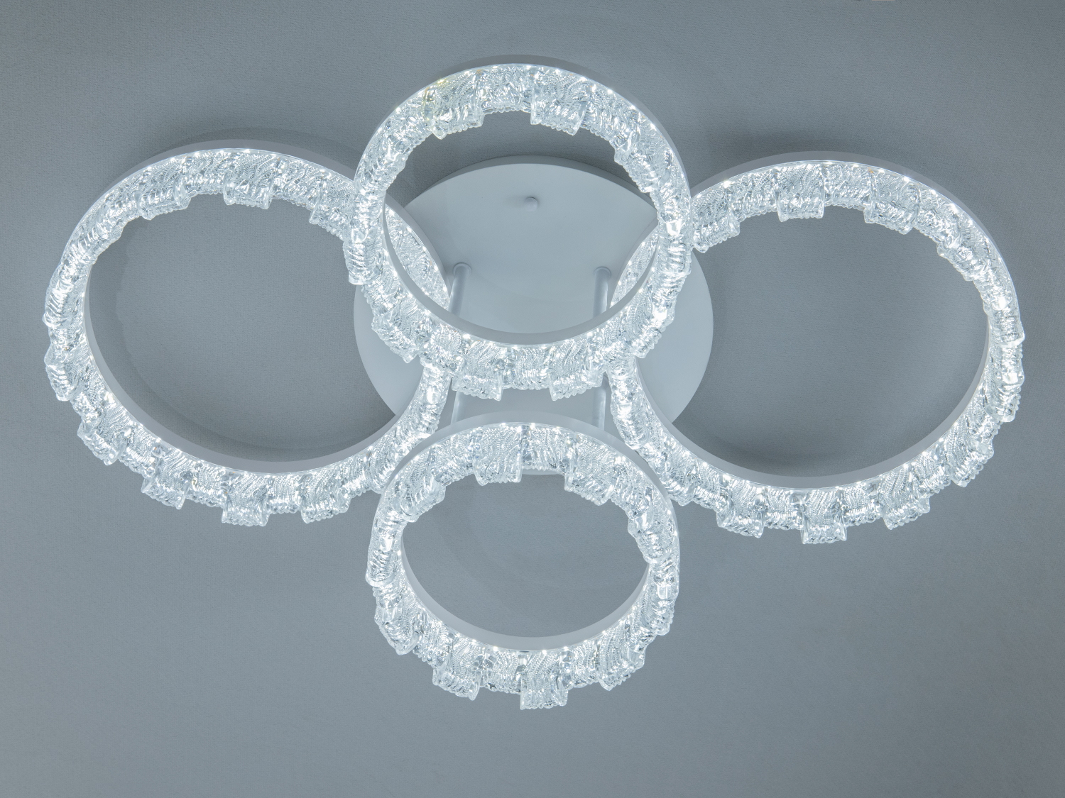 Стельовий світильник з чотирма кільцями, що випромінюють холодне біле світло. Підходить для офісних просторів.