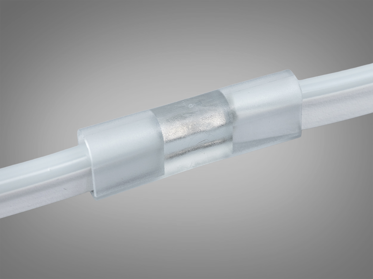 З′єднувач для світлодіодних стрічок, встановлений на двох білих кабелях, забезпечує надійний контакт.