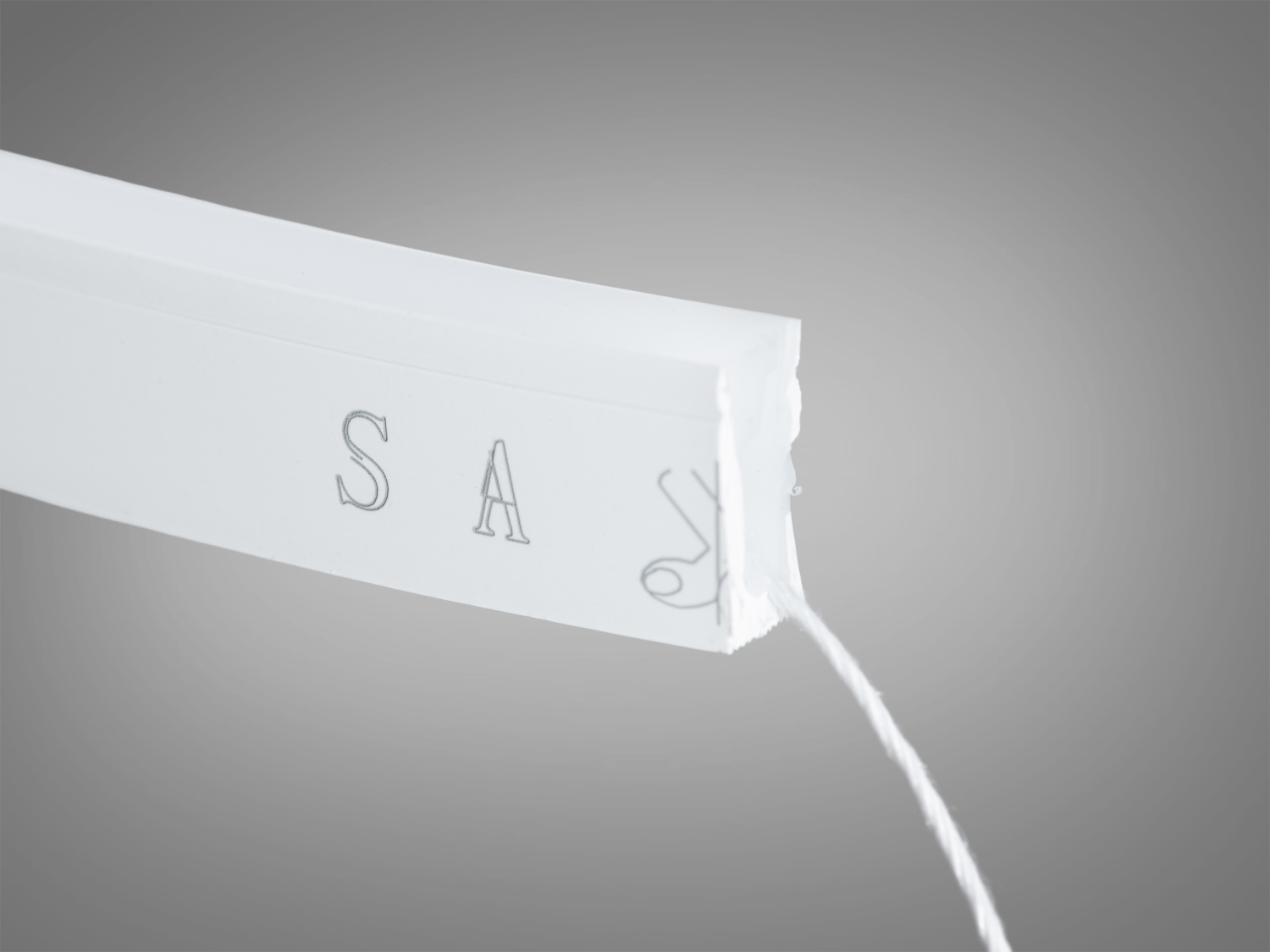 Кінець світлодіодної стрічки з видимими літерами на білій поверхні. Призначена для монтажу в різноманітних інтер′єрах.