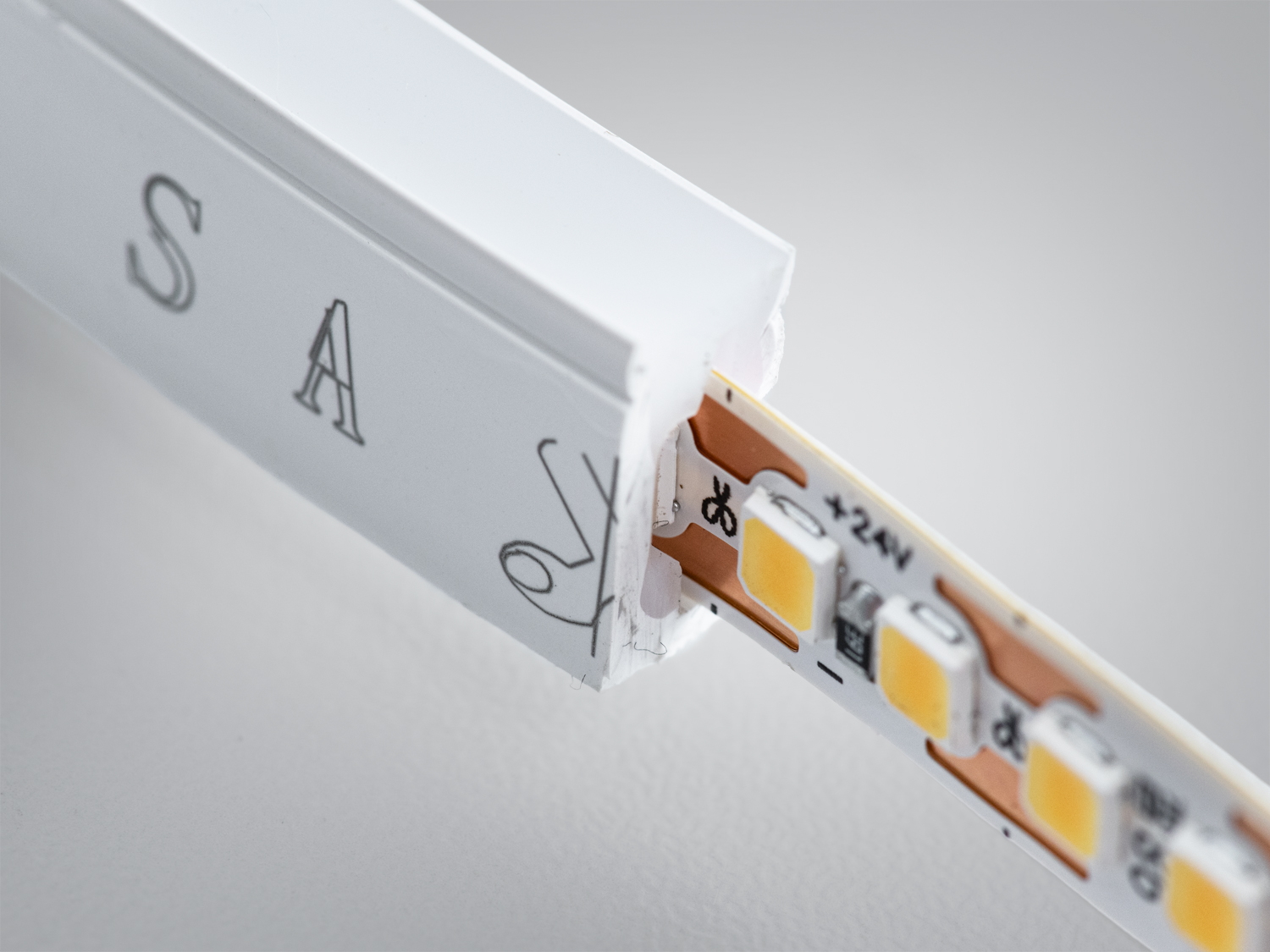 Деталь світлодіодної стрічки з видимими діодами і монтажною частиною. Використовується для підсвічування в приміщеннях.