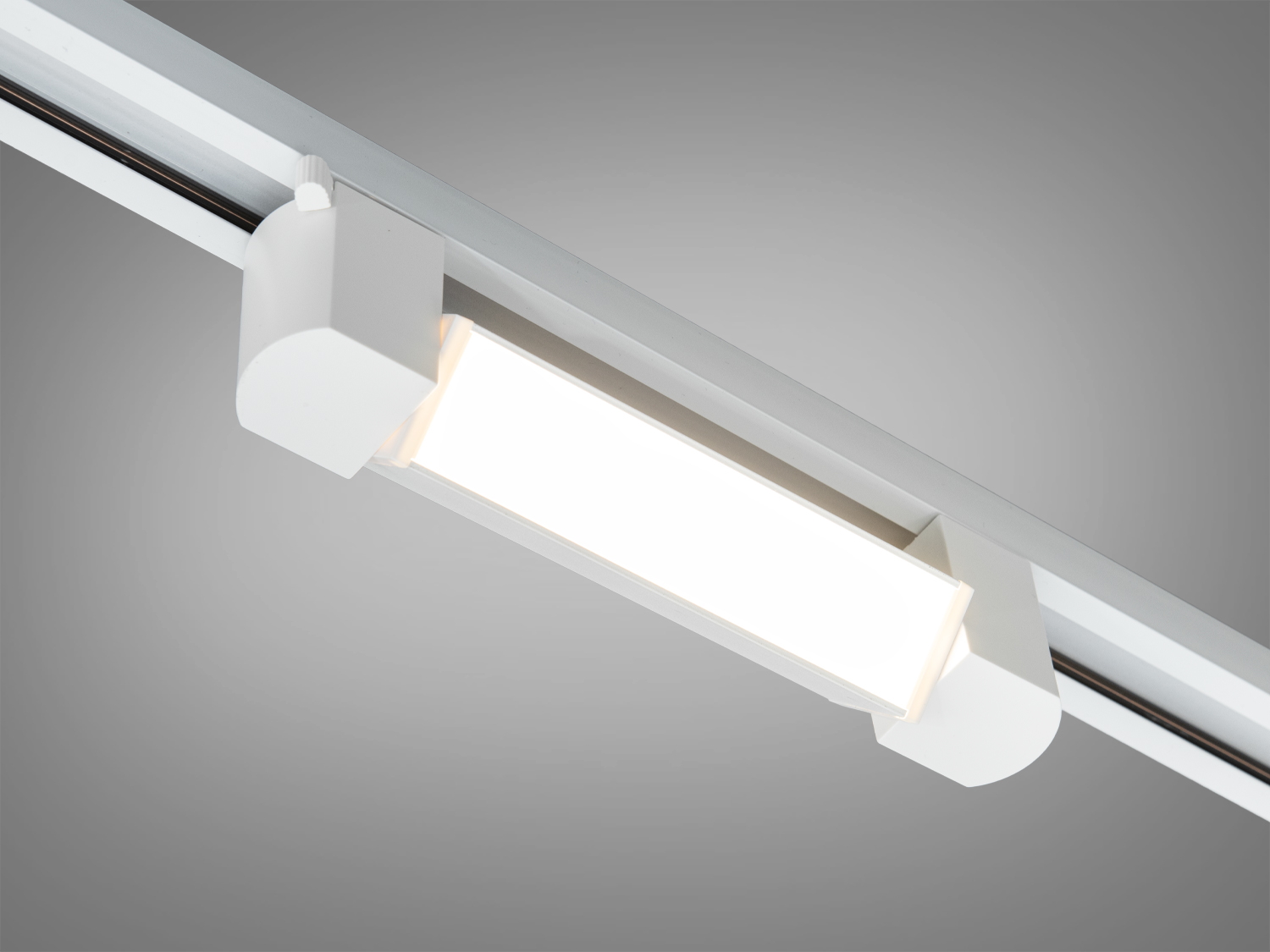 Світлодіодний трековий світильник білого кольору з прямокутним корпусом, підходить для монтажу на стелі, забезпечує рівномірне освітлення.