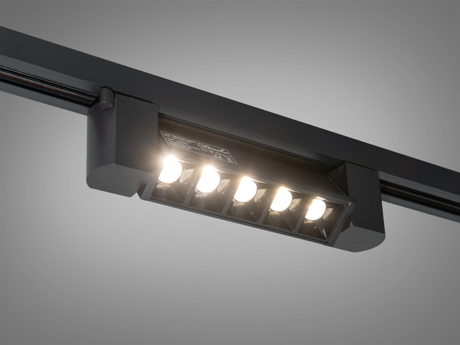 Чорний трековий світильник з увімкненими лампами, забезпечує яскраве освітлення в інтер′єрі.