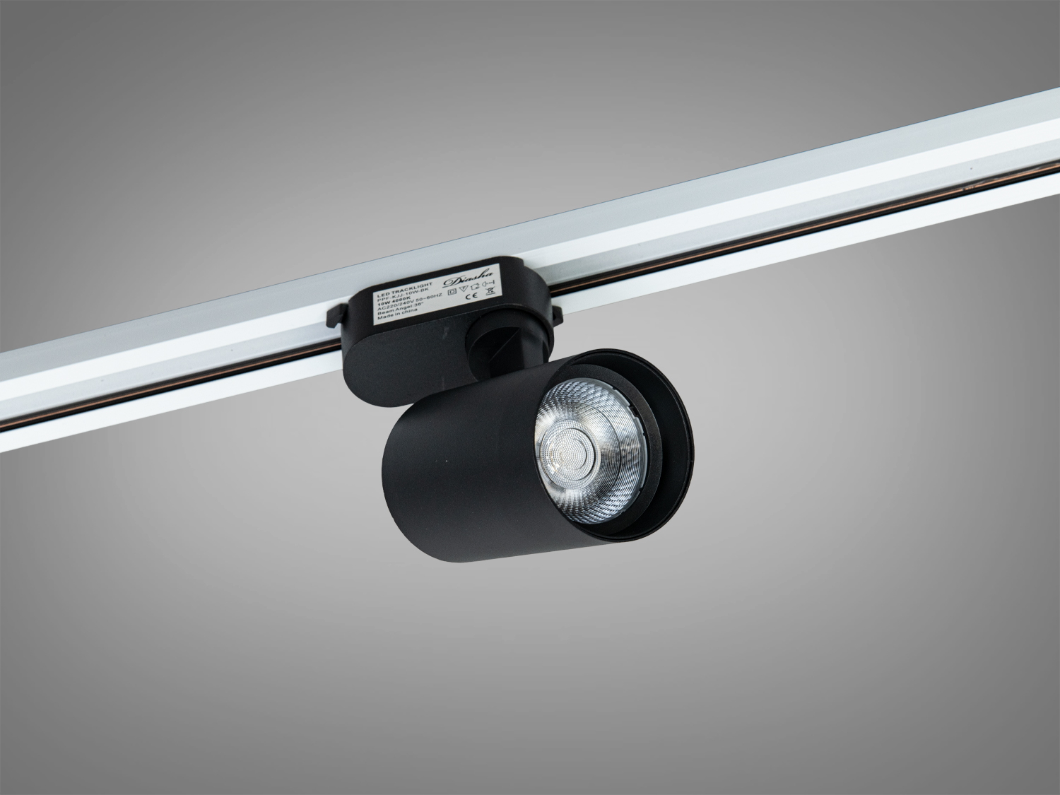Чорний LED-світильник з рефлектором, закріплений на шинопровід для спрямованого освітлення. Використовується в торгових приміщеннях.