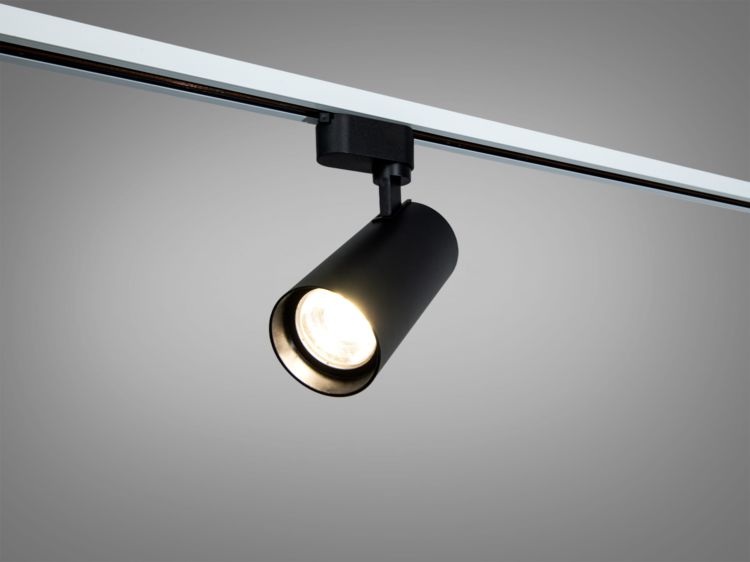 Чорний циліндричний трековий світильник з теплим світлом, закріплений на стелі, ідеально підходить для акцентного освітлення інтер′єру.