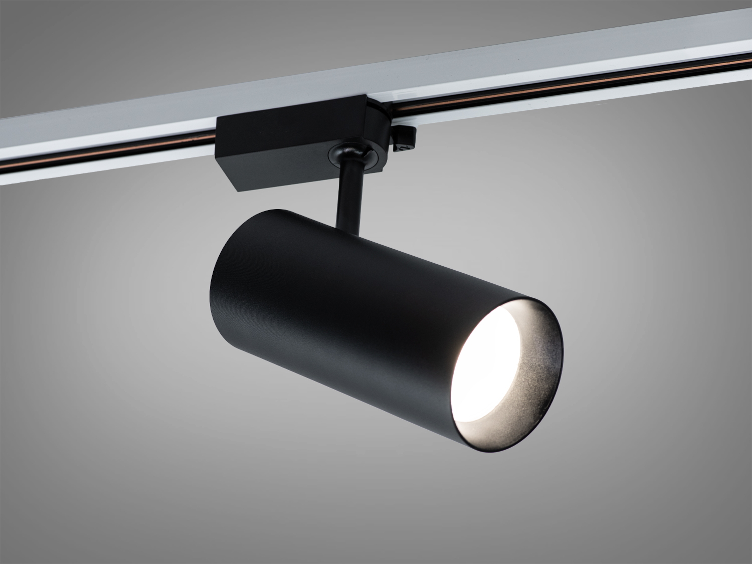 Чорний циліндричний трековий світильник з м′яким розсіяним світлом, підходить для акцентного освітлення в сучасних інтер′єрах.