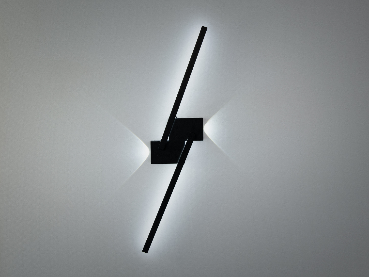 Настінний світильник з чорними лініями, що перетинаються, створює м’яке біле світло. Підходить для сучасного інтер’єру.